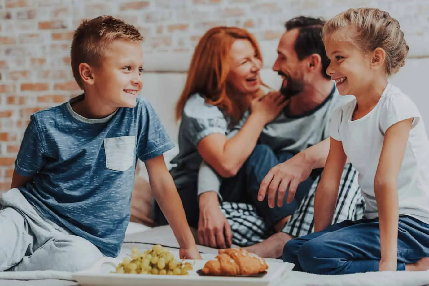 A child enjoying birthday breakfast in bed with a candle.